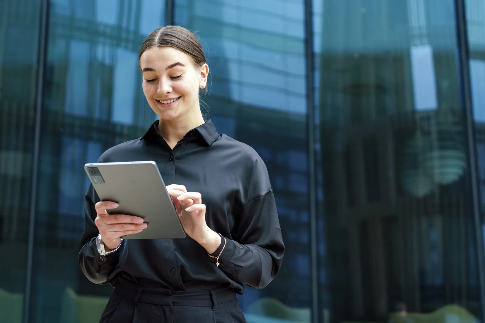 A registry officer reviewing an application on a tablet outside a glass office building